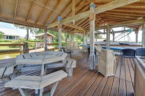 Un terrazzo in legno coperto con tavoli e sedie da picnic, con vista su un corpo d'acqua.