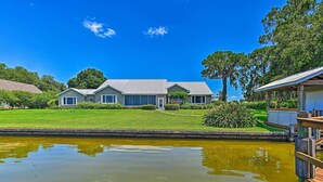 A house with a large lawn and a pond in front. - Waterfront Lake Placid Home with Private Dock! (Lake Placid)