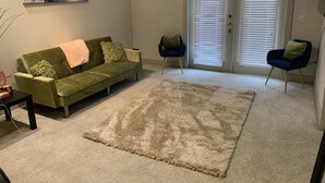 A living room with a green sofa, two armchairs, a large abstract painting, and a beige rug. - Apartment w/ Pool view 5 min from Galleria (Houston)