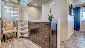 A modern interior with a staircase, a beige armchair, a dark wooden dresser, and a potted orchid. - Amazing Private Rooftop Deck : Walk to Restaurants! (Dallas)