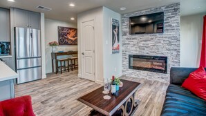 A modern kitchen with a stainless steel refrigerator, a dining area with a wooden table and chairs, and a living room with a fireplace and a sofa. - Amazing Private Rooftop Deck : Walk to Restaurants! (Dallas)