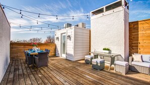 A wooden deck with a dining table and chairs, a small table with a plant, and wicker furniture. - Amazing Private Rooftop Deck : Walk to Restaurants! (Dallas)