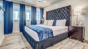 A bedroom with a large bed, a dark headboard, a nightstand with a lamp, and a ceiling fan. - Amazing Private Rooftop Deck : Walk to Restaurants! (Dallas)