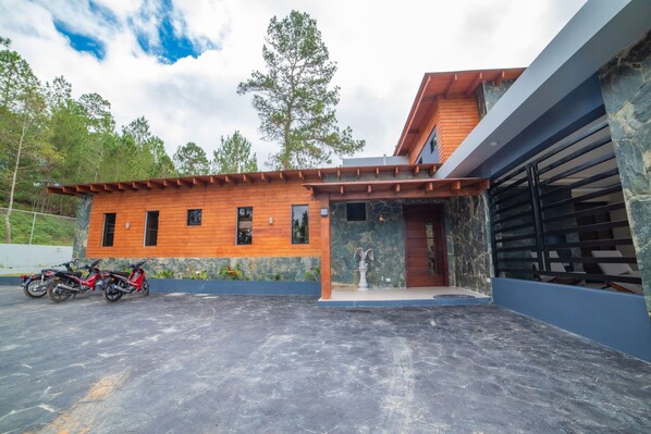 A modern house with a garage, a covered patio, and a stone wall.