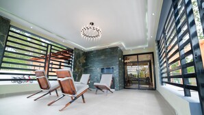 A modern interior with a stone wall, a fireplace, and a seating area with chairs. - VILLA SEGURA VICENTE (Constanza)