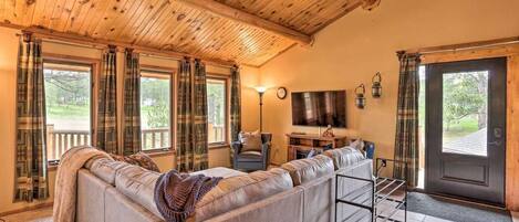 A cozy living room with a leather sofa, a television, and a wooden ceiling.