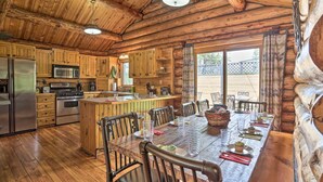 A log cabin-style kitchen with wooden cabinets, a central island, and a dining table set for four.