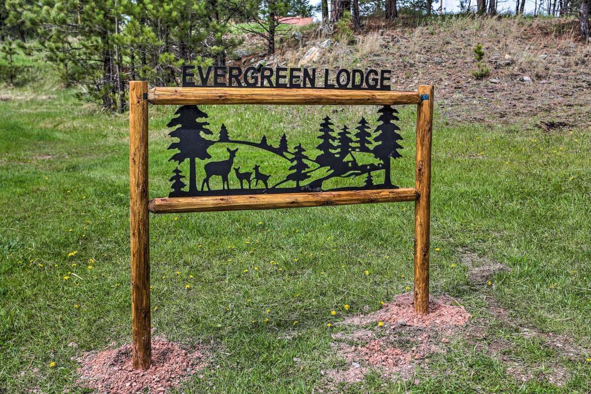 A wooden sign with the text "Evergreen Lodge" and silhouettes of deer and trees.