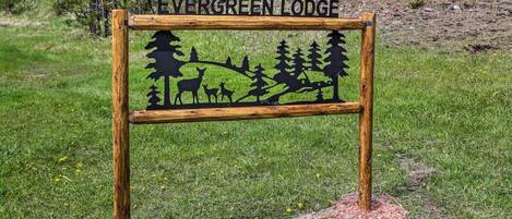 A wooden sign with the text "Evergreen Lodge" and silhouettes of deer and trees.