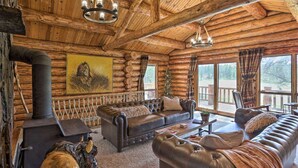 A log cabin interior with a fireplace, leather sofas, and a large painting.