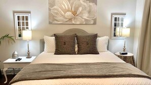 A hotel room with a large bed, two bedside tables, a wall-mounted painting, and a window with curtains. - Skyline Views/3 Miles to Downtown/WeeklyDiscounts/Pet Friendly (Nashville)