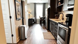 Une cuisine moderne avec un plancher en bois, des appareils en acier inoxydable et un coin repas comprenant une table et des chaises.