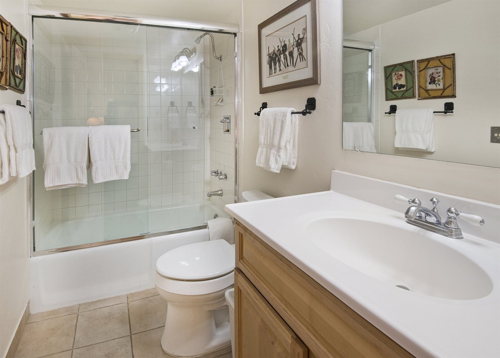 Un bagno con doccia vetrata, un WC bianco, un mobiletto in legno con lavandino e uno specchio grande.