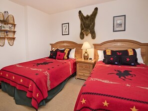 A hotel room with two beds, each with a red blanket featuring star patterns, wooden headboards, and matching pillows.