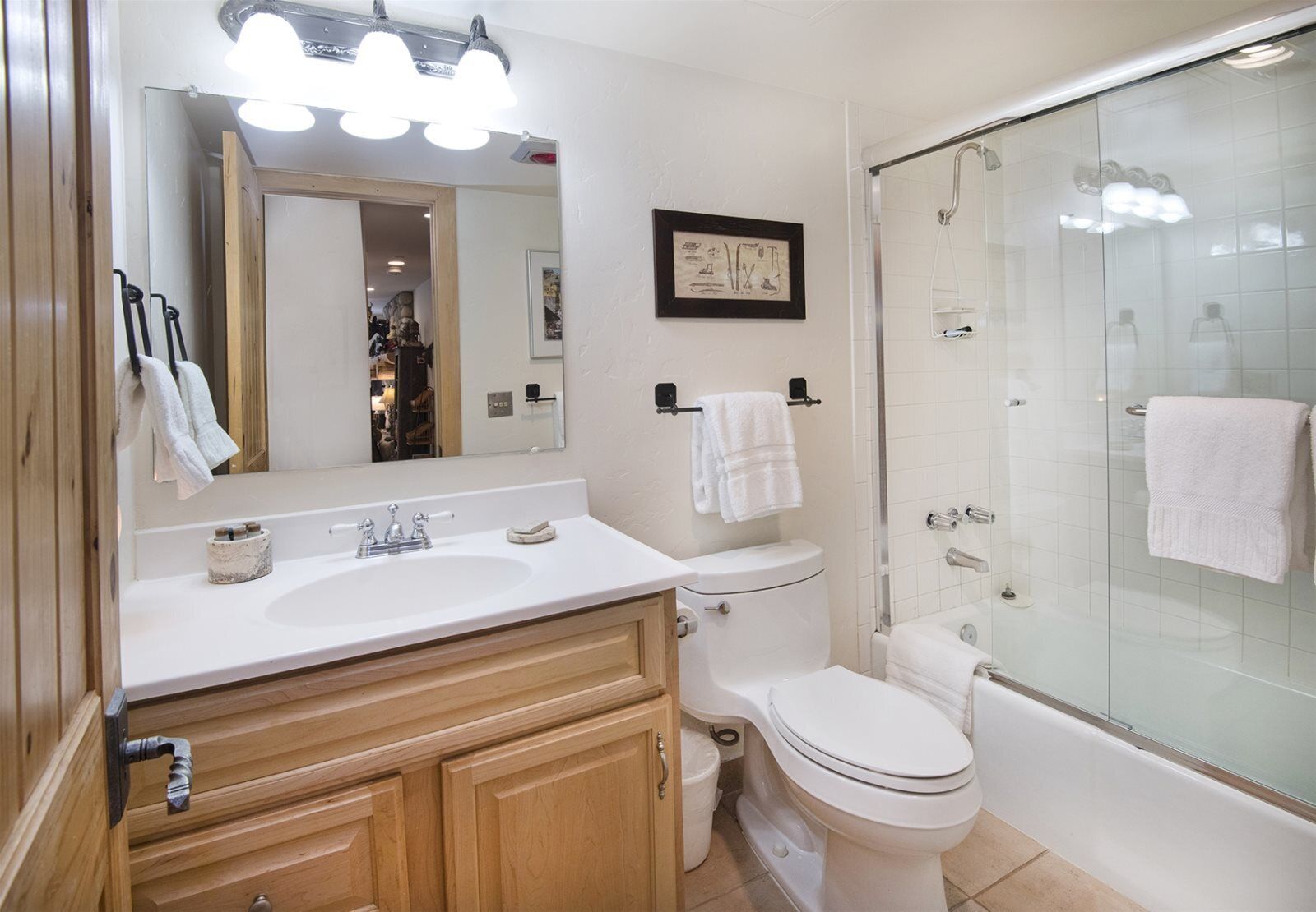 A modern bathroom with a white sink, toilet, and glass-enclosed shower.