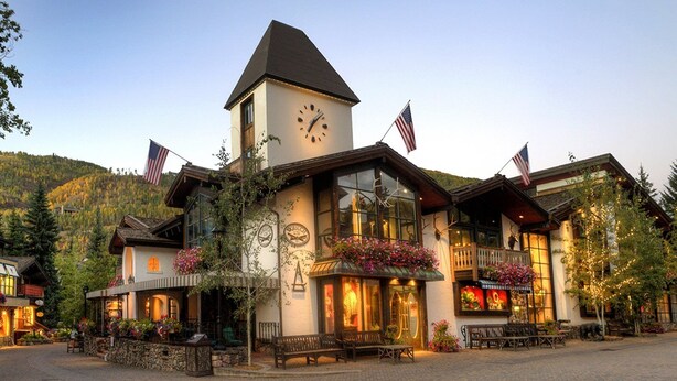 Ein Hotel mit einem Glockenturm, amerikanischen Flaggen und Außenbestuhlung.
