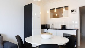 A modern kitchen with a white island, black chairs, and a grey sofa. - Modern & cozy 150m from the Croisette (Cannes)