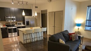 A modern kitchen with dark cabinets, stainless steel appliances, and a bar area with stools. - 1 bd 1 bt 815 sq ft - The BEST location in Midtown (Houston)