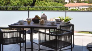 En terrasse med et spisebord og stole, med udsigt over en bakke med bygninger.