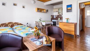 Une pièce confortable comprenant un lit, un bureau en bois, une chaise et un coin cuisine.