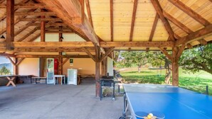 Un espace de loisirs intérieur comprenant une table de ping-pong, des bancs et un réfrigérateur.