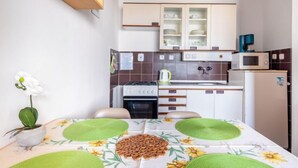 Une cuisine de taille réduite, équipée d’une cuisinière, d’un four à micro-ondes et de placards.