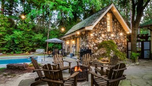 A stone building with a fire pit and outdoor seating. - Enchanted Oasis: Walk to Village, Pool, Hot Tub, Putting Green, 3 Houses (Pinehurst)