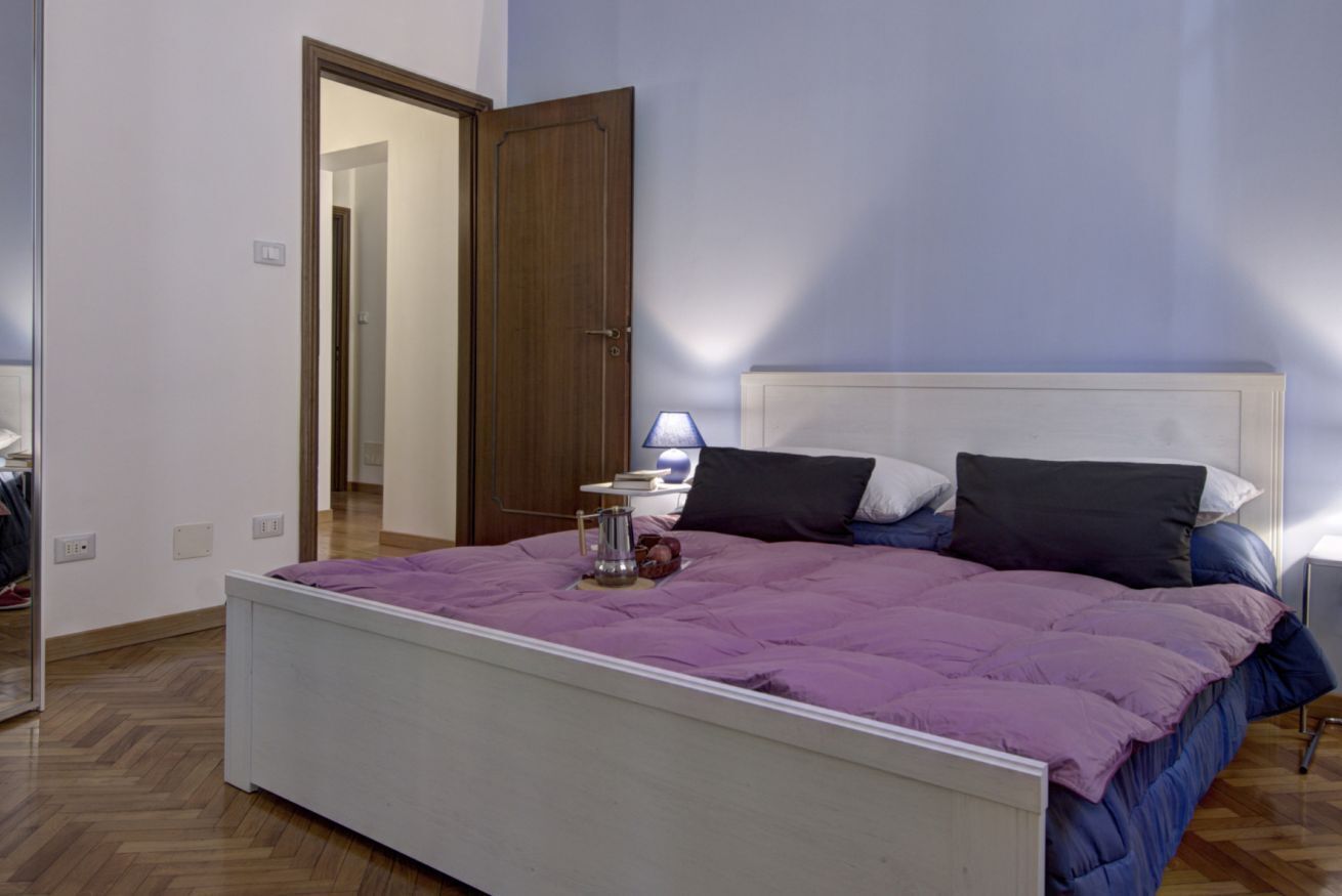 Une chambre à coucher avec un lit, une table de chevet, une lampe et une porte.