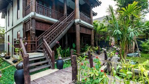 A traditional wooden house with a wooden staircase leading to a porch. - Java Wooden Villa by AIC (Siem Reap)