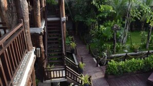 A wooden staircase leading to a balcony with a view of a lush garden. - Java Wooden Villa by AIC (Siem Reap)
