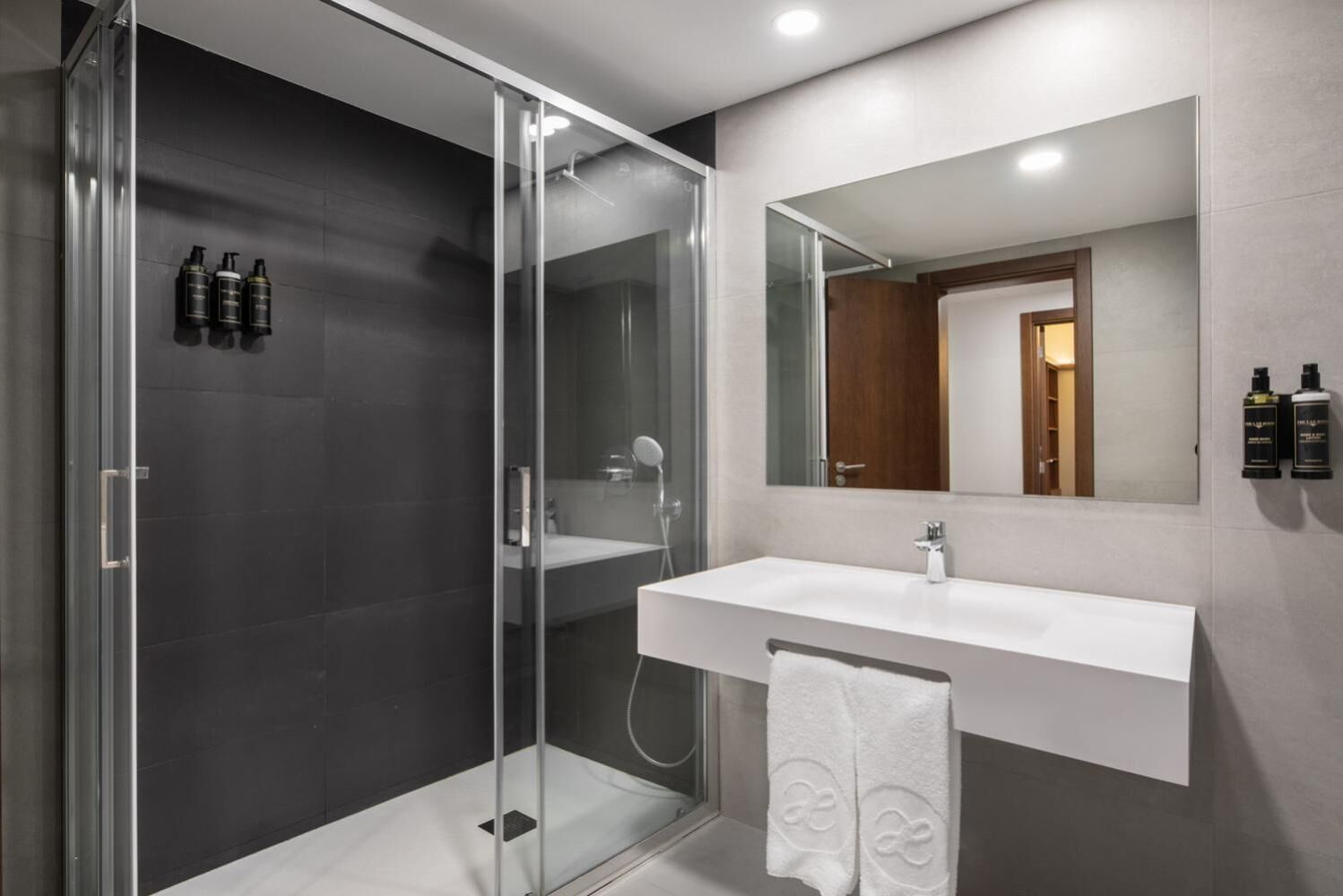 A modern bathroom with a glass shower enclosure, a white sink, and a large mirror.