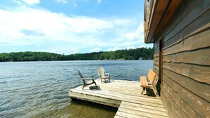 A wooden dock extending into a lake with two Adirondack chairs and a bench. - Sunset Retreat Lake Rosseau  (Rosseau)