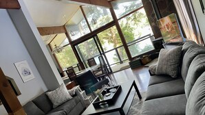 A modern living room with a large sectional sofa, a coffee table, and a dining area with chairs and a table. - Sunset Retreat Lake Rosseau  (Rosseau)