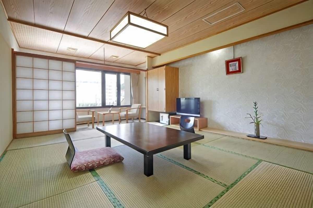 A traditional Japanese room with tatami flooring, a low table, a television, and sliding doors.