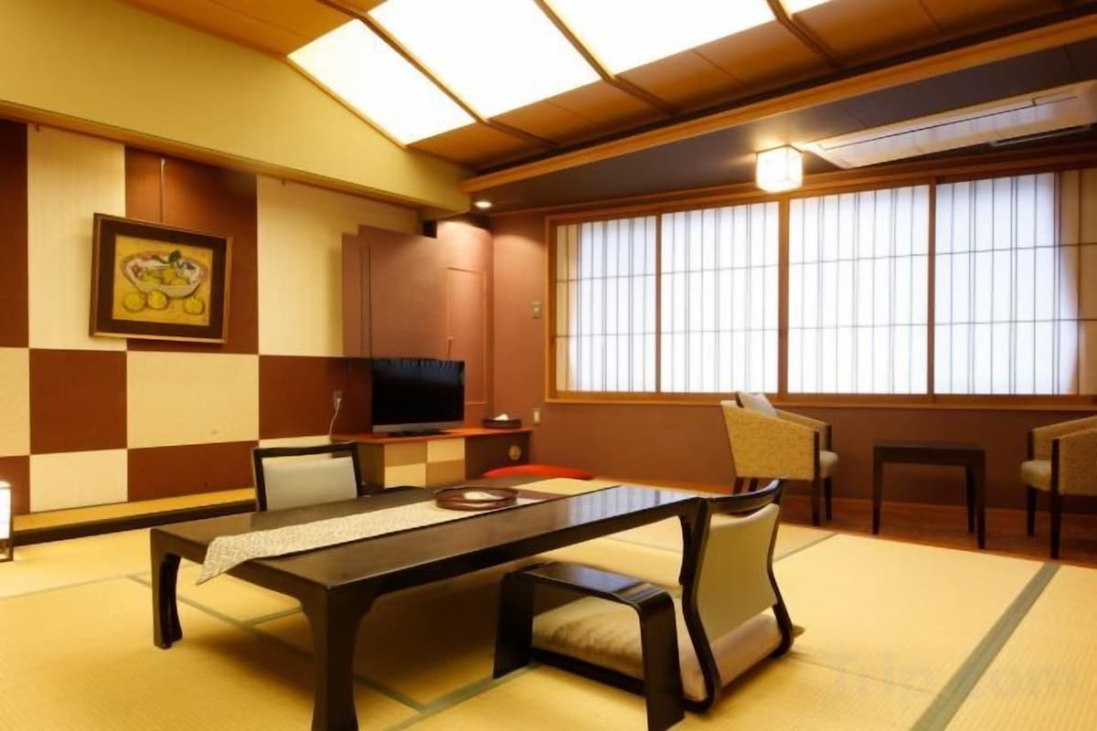 A traditional Japanese-style room with tatami flooring, a low table, and a television.