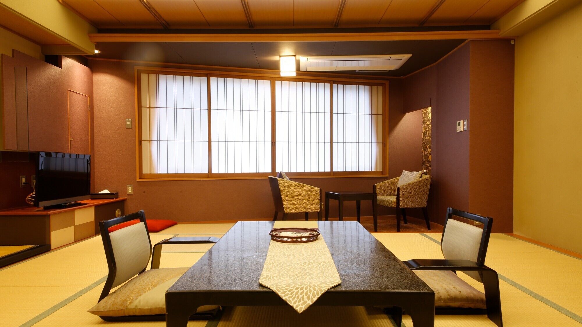 A traditional Japanese-style room with tatami flooring, a low table with a woven mat, and sliding shoji doors.