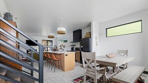 A modern kitchen with a central island, bar stools, and a dining table with chairs. - Modern on Main-Walking Distance to Downtown Hill City and Mickelson Trail! (Hill City)