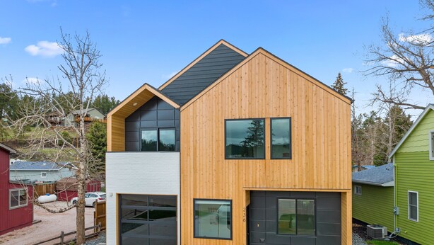 A modern two-story house with a garage, a large window, and a wooden exterior. - Modern on Main-Walking Distance to Downtown Hill City and Mickelson Trail! (Hill City)