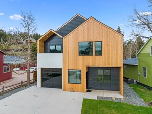 Ein modernes, zweistöckiges Haus mit Garage, großem Fenster und Holzfassade.