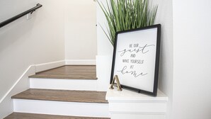 Eine Treppe mit einem Podest, auf dem ein gerahmter inspirierender Spruch, eine Pflanze und ein kleines Dekorationsstück stehen.