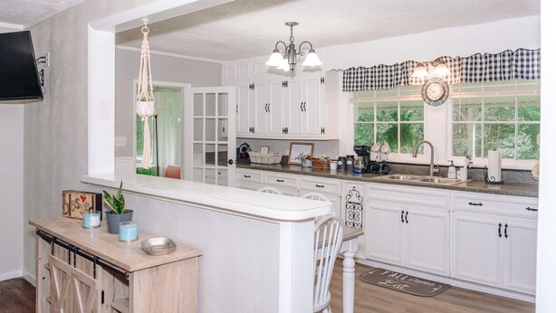 A kitchen with white cabinets, a wooden bar counter, and a hanging light fixture. - Pet Friendly Quiet Retreat Near Nashville (Kingston Springs)
