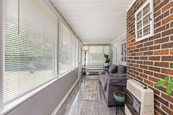 A narrow, enclosed hallway with a grey floor, a grey sofa, and a radiator on the right.