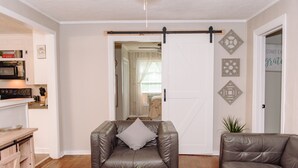 A living room with a brown leather chair, a brown leather sofa, and a wooden coffee table. There is a sliding barn door in the background. - Pet Friendly Quiet Retreat Near Nashville (Kingston Springs)