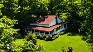A white house with a red roof surrounded by lush green trees. - Pet Friendly Quiet Retreat Near Nashville (Kingston Springs)