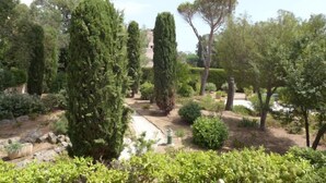 A landscaped garden with various trees and shrubs, a stone pathway, and a small water feature. - La Chênaie by Interhome (Saint Aygulf)