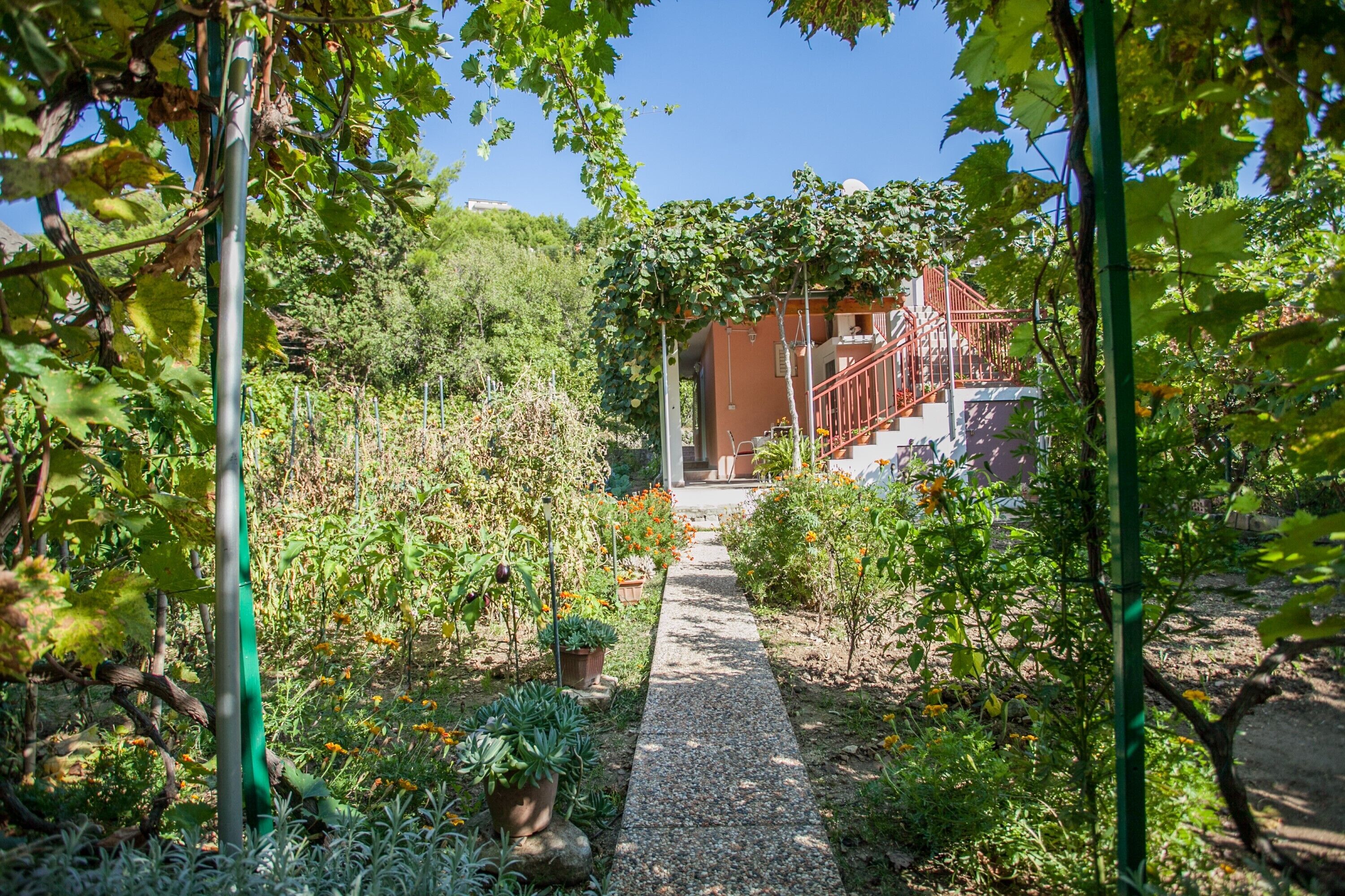 A garden pathway leading to a building with a red staircase.