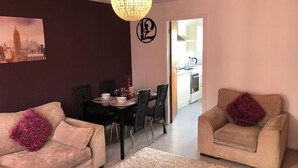 Ein Wohnzimmer mit zwei Sofas, einem Esstisch und einer Kronleuchter.