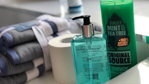 Ein Badezimmer-Schrank mit Handseife, Duschgel, einem Handtuch und einer Toilettenpapierrolle.