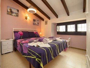 Um quarto com uma cama, mesas de cabeceira, uma janela e obras de arte nas paredes.
