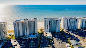 Um hotel moderno com vários andares, um estacionamento e vista para o oceano.